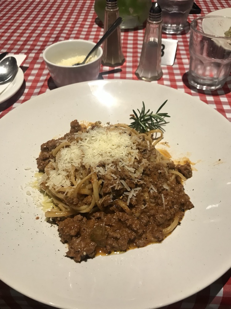 Spaghetti bolognese with parmesan and a sprig of rosemary